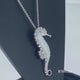 Load and play video in Gallery viewer, Jewelili Sterling Silver with Created Opal and White Round Diamonds Seahorse Pendant Necklace
